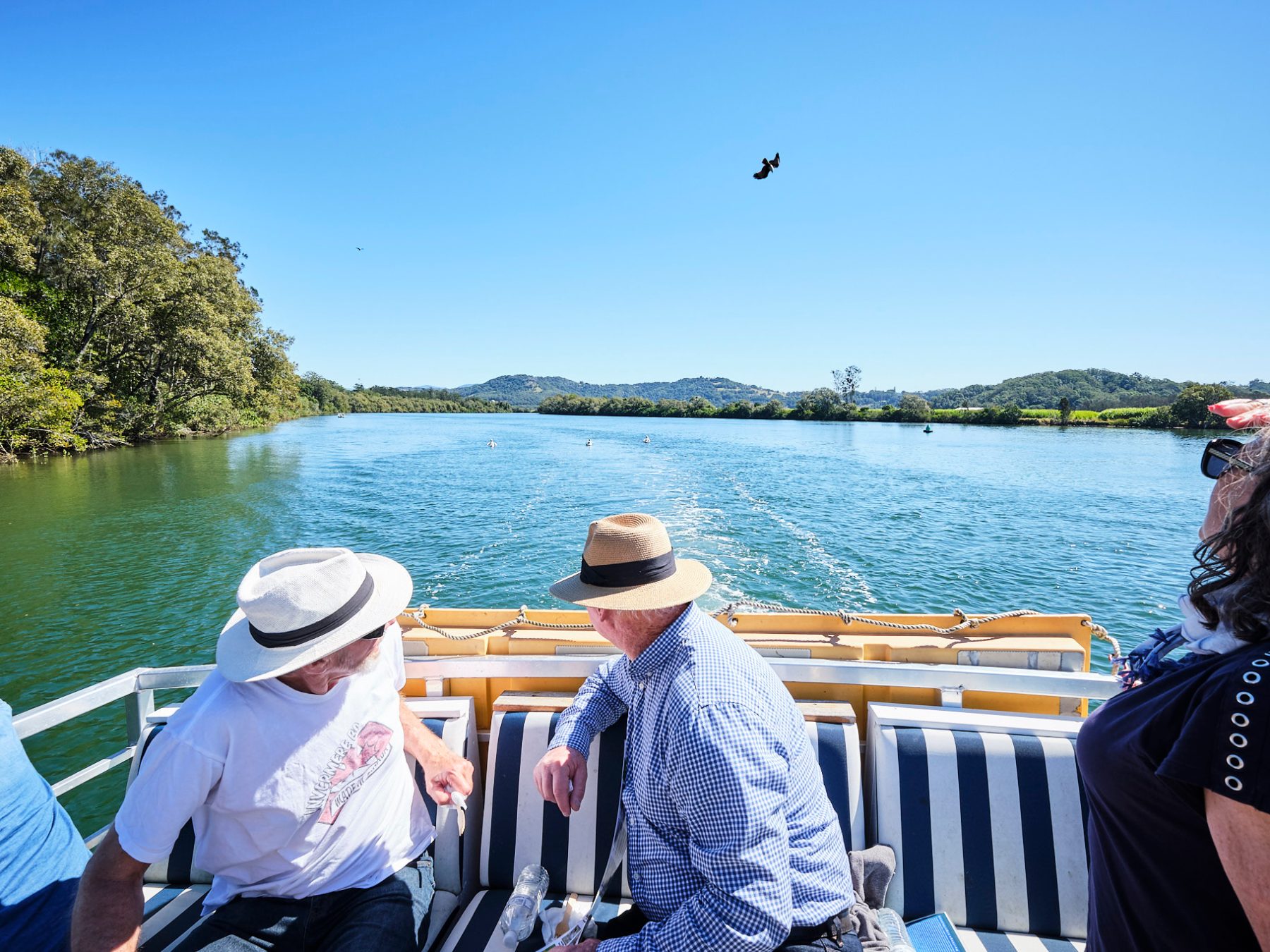 a group of people sitting on a bench next to a body of water