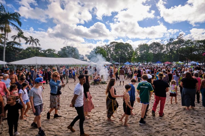 a group of people standing next to a crowd of people at a beach